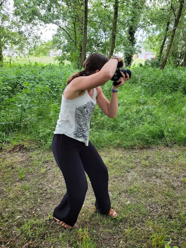 une femme photographe prend une photo pendant un shooting en exterieur